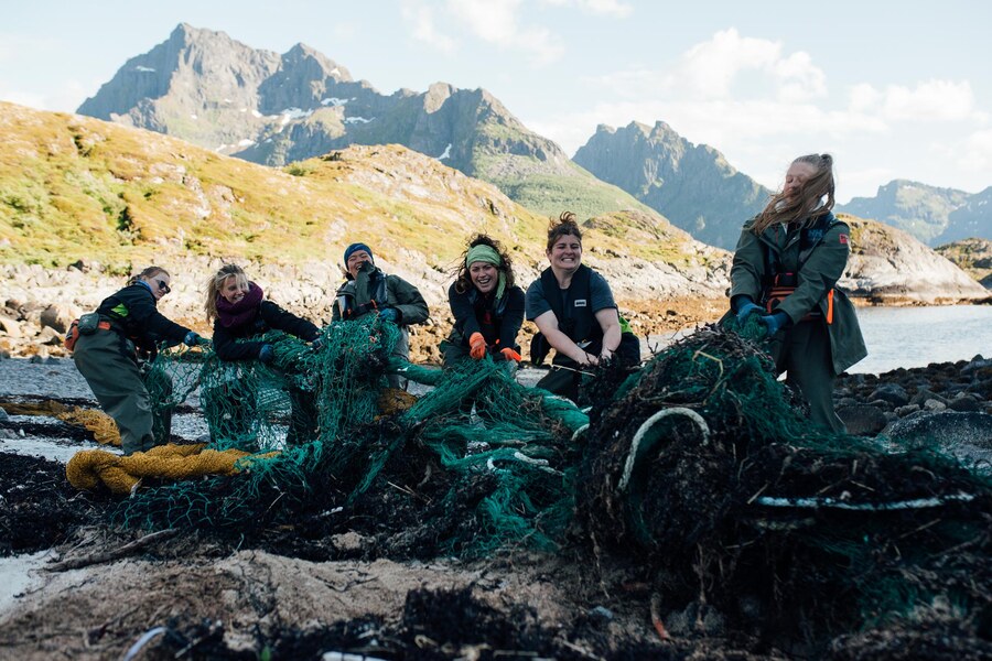 Beach-cleaning crew hauling a discarded fishing net ashore